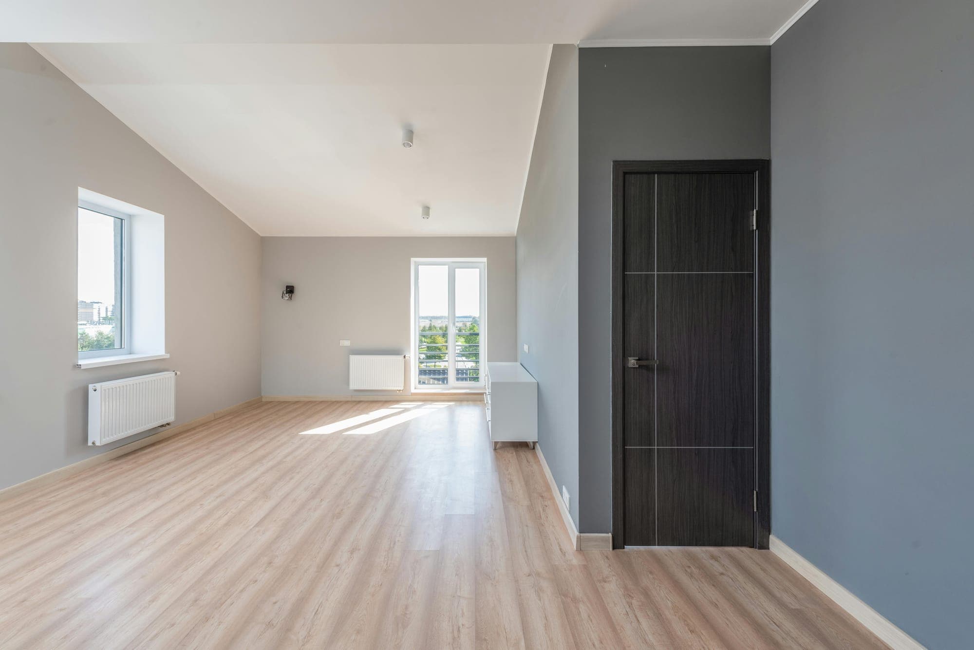 Freshly painted empty room with gray walls and light wood floors