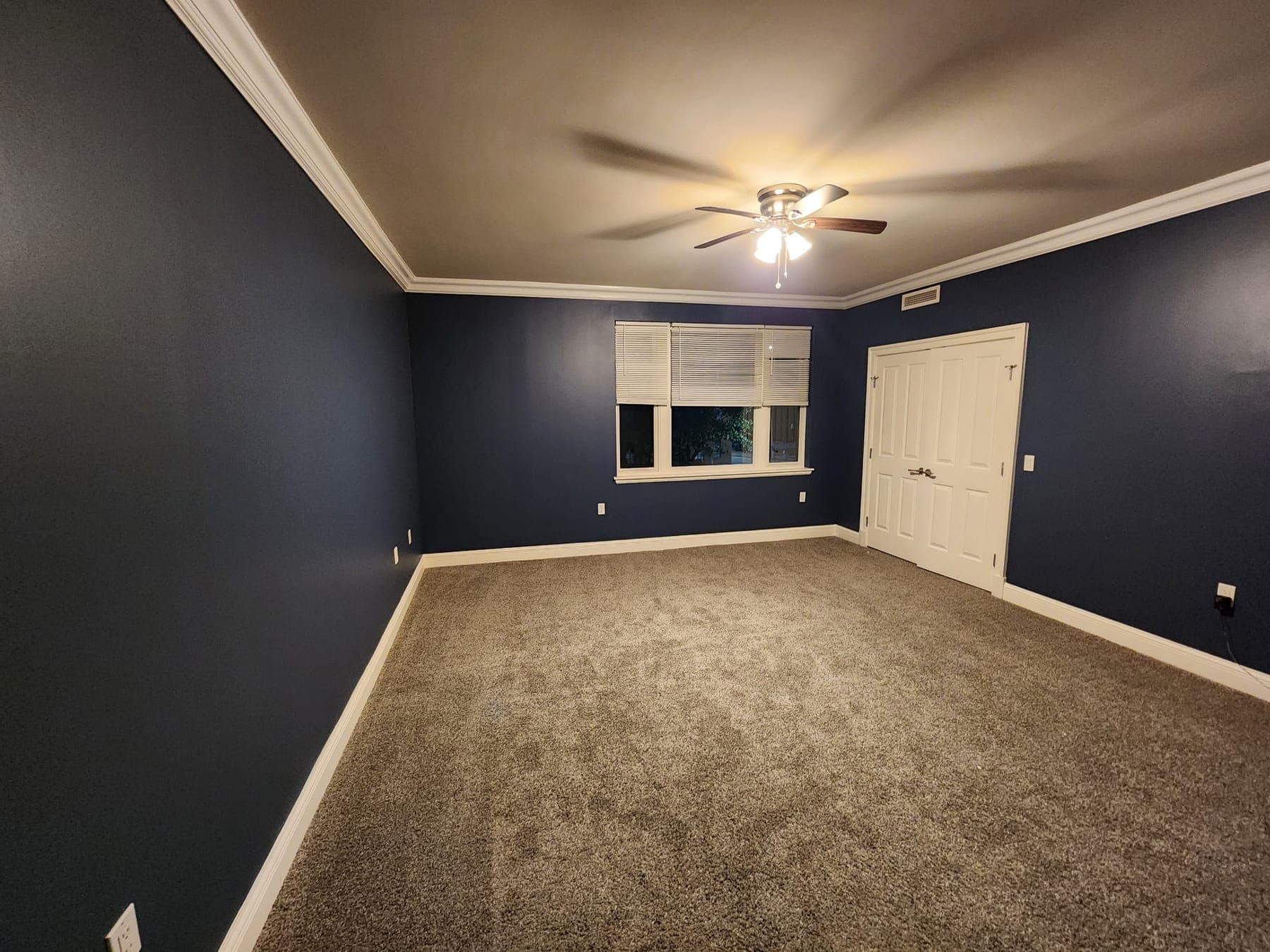 Bedroom painted deep navy with white crown molding by Elite Finishes